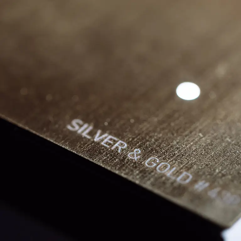 Close-up of QLOCKTWO EARTH 45 Creator's Edition Silver & Gold metal surface crafted with silver and gold leaf